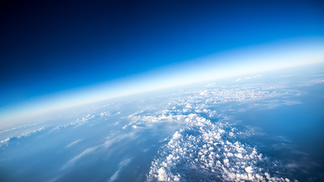 Curvature of the Earth with cloud fields and deep blue sky from a great height.